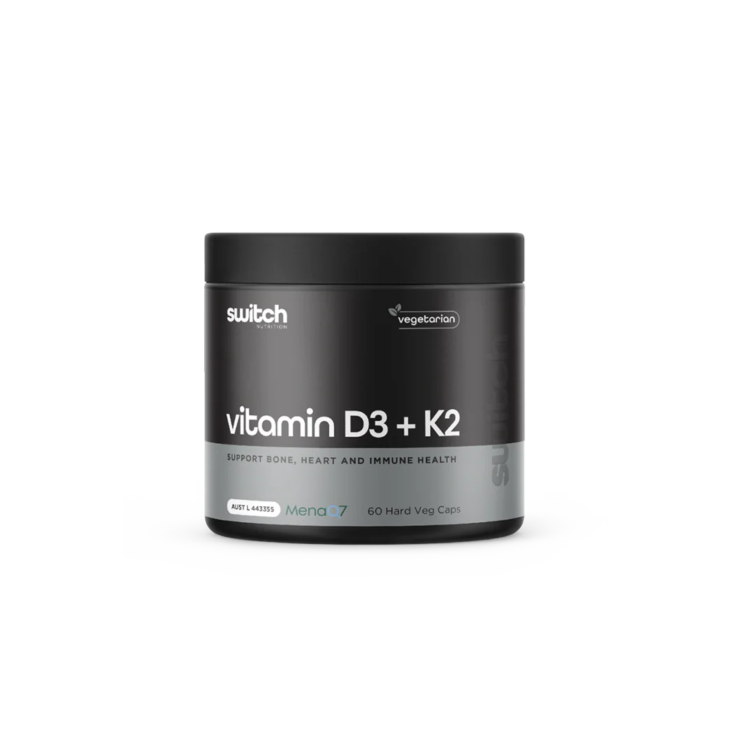 Black supplement container labeled 'vitamin D3 + K2' by switch on a white background